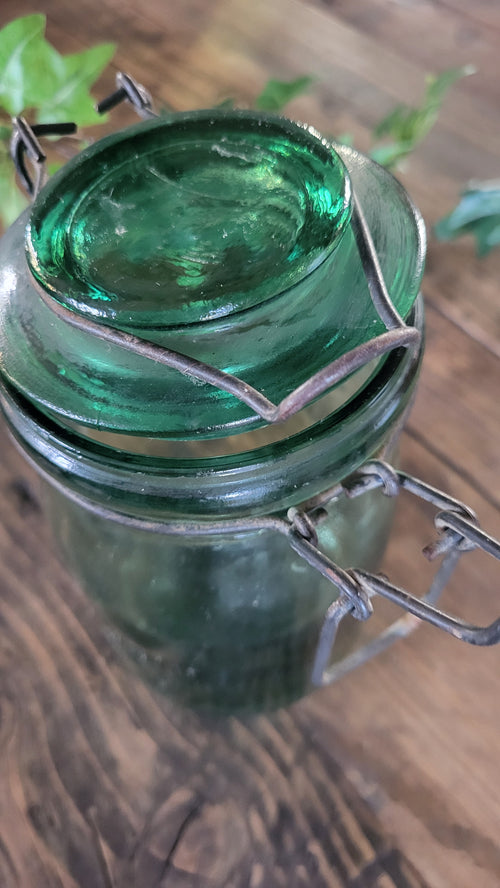 Green glass bottle with silver wire wrapping on a wooden surface