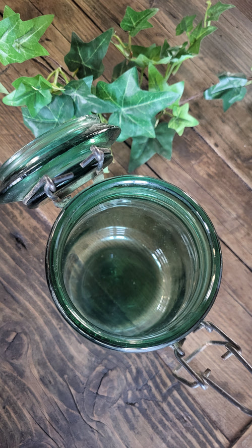 Green glass mug on a wooden surface with a plant